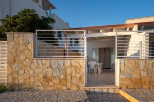a house with a stone wall and a patio at Frontemare in Porto Cesareo