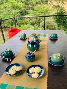 a table with teapots and cookies on plates at Dumbara Breeze in Hunnasgiriya