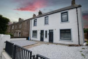 a white house with black doors and windows at Penthouse at the White House near Edinburgh in Bathgate