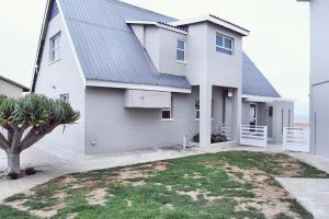 a white house with a gray roof at Palm Villa Beachfront Accomodation in Hentiesbaai