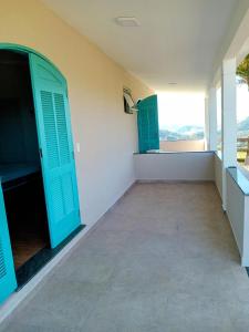 a empty room with green doors and a balcony at Pousada das Colinas in Águas de Lindóia
