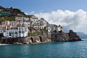 een groep witte gebouwen op een heuvel naast het water bij B&B Palazzo Pisani in Amalfi