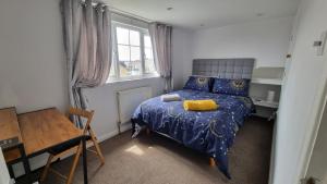 a bedroom with a bed and a table and a window at Spencer , 4 bed slp 8 semi in Lee On The Solent in Lee-on-the-Solent