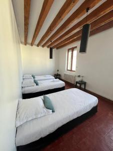 three beds in a room with wooden ceilings at Les Combres in La Daguenière +4 photos