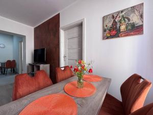 a dining room with a table with orange chairs at Apartament A - Rynek 4, Pasym l centrum l 2 sypialnie in Pasym