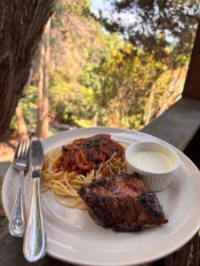 a plate of food with pasta and meat on a table at Paradise of Atitlan in Santiago Atitlán +22 photos