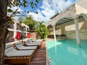 a swimming pool with lounge chairs next to a house at Frater Yucatán Hotel in Valladolid