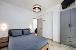 a bedroom with a blue bed and a tv at Honeymoon Beach Studios in Perivolos