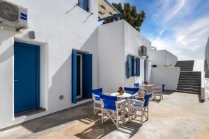 a patio with blue doors and tables and chairs at Honeymoon Beach Studios in Perivolos +128 photos