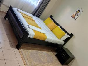 a bed with yellow pillows on it in a room at Elegant 2 Bedroom Apartment close to Rupa Mall, Noble Hotel,Poa PLace, Mediheal hospital, TopHill Hospital and St Lukes Hospital in Eldoret
