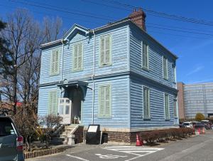 a blue house with white shutters on a street at Irest Village Matsumoto in Matsumoto