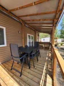 a patio with a table and chairs on a deck at Mobil home luxe 3 ch dont une suite parentale clim terrasse bois couverte La Yole 5 étoiles in Vendres