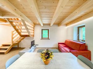 a living room with a table and a red couch at Luxury Chalet Dolomiti-Campiglio-Trentino in Porte di Rendena