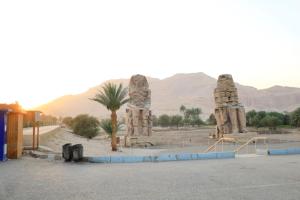 a parking lot with two stone statues in the desert at Tomorrow Land villa in Luxor