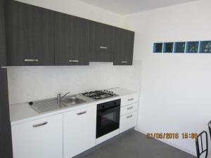 a kitchen with white cabinets and a sink and a stove at Appartamento Emma in Faver