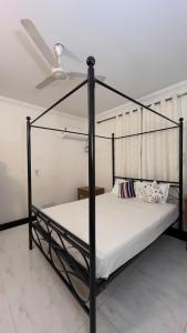 un letto a baldacchino nero in una stanza con soffitto di 2BHK Flat in Arpora, 10 mins from Baga Beach ad Arpora