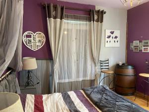a bedroom with purple walls and a bed with curtains at Les chambres de cathy in Labastide-Murat