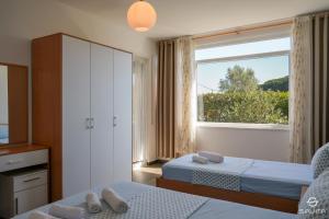 a bedroom with two beds and a large window at Gjiri i Lalzit - Savita Apartments - Kompleksi Turistik Lura 2 in Mullini i Danit