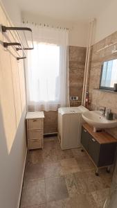 baño con lavabo, bañera y ventana en DebRentZen Station Apartman - business plus, en Debrecen