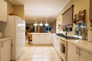 a large kitchen with white cabinets and a white refrigerator at Franskraal Bed and Breakfast Pty Ltd in Franskraalstrand