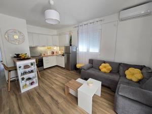 a living room with a gray couch and a kitchen at Moderan apartman Klaudija in Igalo