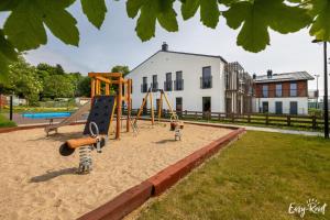 two children playing on a playground in the sand at Apartament Konik Morski - z basenem - Easy - Rent Apartments in Trzęsacz