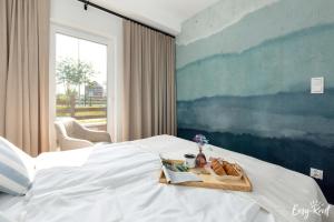 a white bed with a tray of bread and a window at Apartament Konik Morski - z basenem - Easy - Rent Apartments in Trzęsacz +53 photos