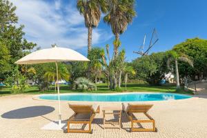a table and two chairs and an umbrella next to a pool at Quinta das Tílias in Santiago do Cacém