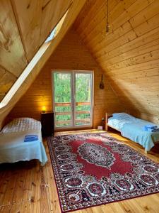 a attic room with two beds and a rug on the floor at Leśne zacisze nad Narwią in Ostrykół Włościański