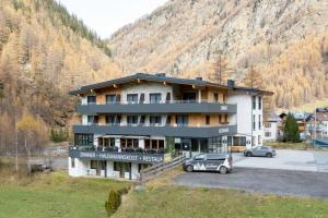 a large building with cars parked in a parking lot at Gasthof Brückenwirt Hotel in Sölden