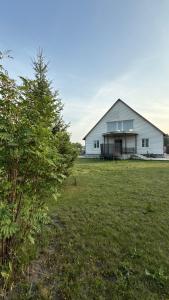ein großes weißes Haus auf einem Feld mit einem Baum in der Unterkunft Wood house ukg in Öskemen