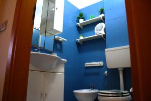 a blue tiled bathroom with a toilet and a sink at Summer House in Buonfornello