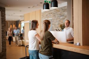 two women and a man standing at a counter at eduCARE Hotel in Treffen