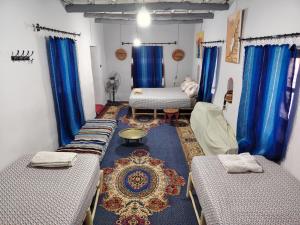 a room with three beds and blue curtains at DAR JOUD in Tabourakht
