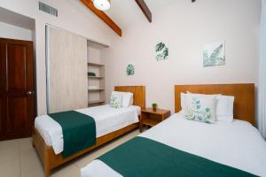 two beds in a room with white and green sheets at Villa Serenidad Costera in Sardinal +55 photos