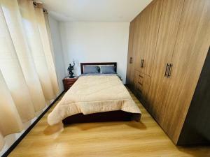a bedroom with a bed and a large wooden cabinet at Sony Cel's Little Corner in Azogues
