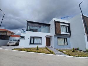 a white house with a car parked in a driveway at Sony Cel's Little Corner in Azogues