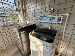深圳Kuaike Xingjiduo Apartment的洗衣机和垃圾桶