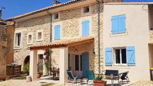 a stone house with blue windows and chairs at Mas la Provinciale in Malaucène