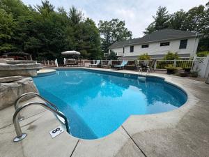 a large blue swimming pool in front of a house at Cheerful 5-bedroom resort with heated pool in East Stroudsburg