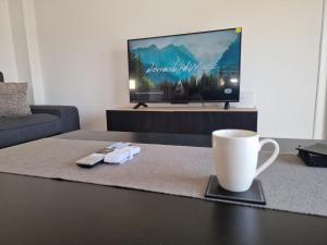 a coffee table with a coffee cup and a tv at Kafkalia Sea Breeze in Larnaca