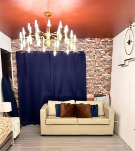 a couch sitting in a living room under a chandelier at Near Airport Beach SwimmingPool HotShower NoElevator Plumera Mactan Condo in Lapu Lapu City +21 photos