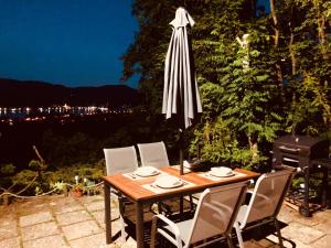a patio table with chairs and an umbrella at night at Erdei Kabin Nagymaros in Nagymaros