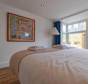 a bedroom with a large bed with a picture on the wall at Margate Old Town & Beach, Stylish 3 bed House with Garden in Margate