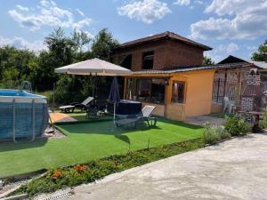 a backyard with a lawn with an umbrella and a house at Lipite Guest House in Yantra
