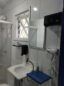 a bathroom with a sink and a mirror and a window at Pousada Cantinho da Mi & Teco in Campos do Jordão