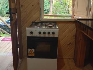 a stove in a kitchen with a window at Bangalô com cozinha Refúgio das borboletas in Itatiaia