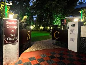 a gate with a sign for a tea garden at night at Scarlet's Cottage & Tea Garden in Cochin