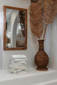 Un jarrón en un estante con un espejo y libros. en Chic Elysium - Serenity, en Naxos Chora