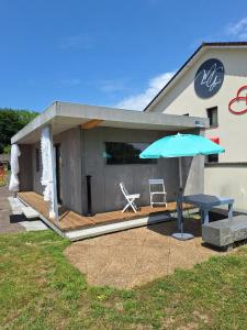 a house with a patio with a table and an umbrella at Maison studio, tiny house, parking privé, jardin in Toul
